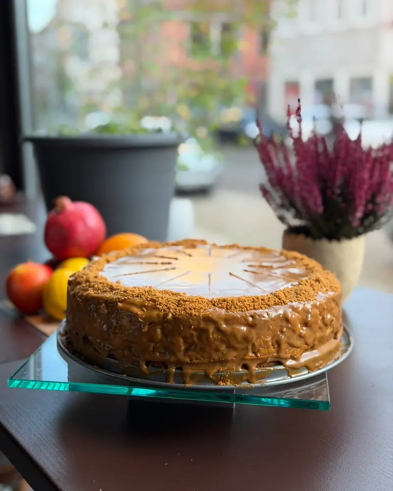 Lotus-Cheesecake mit Karamellguss und Keksbröseln auf einer Glasplatte